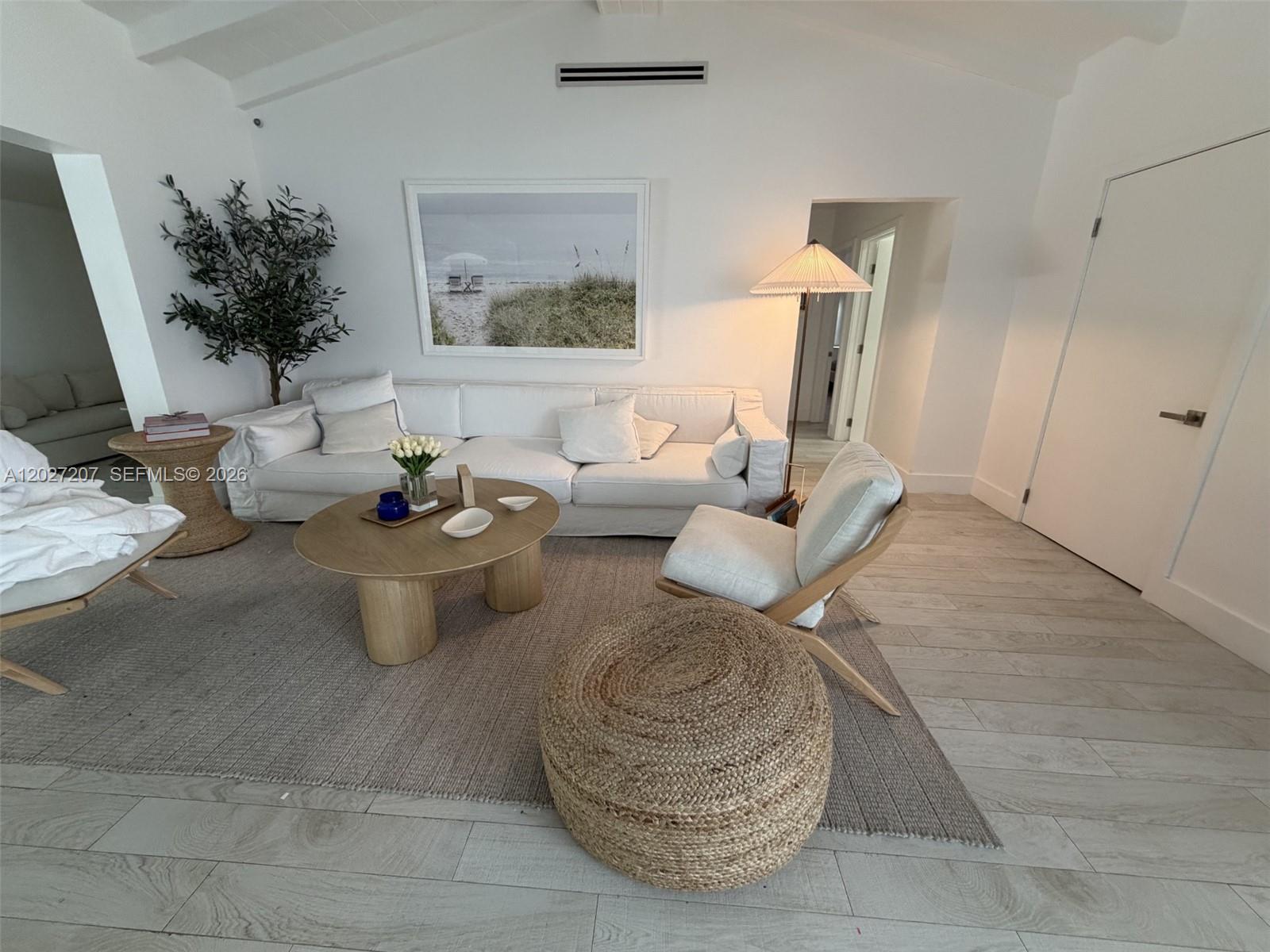 A bright living room features a white sofa, round wooden coffee table, and jute ottoman — 665 Allendale Rd, Key Biscayne FL 33149, KEY BISCAYNE, FL