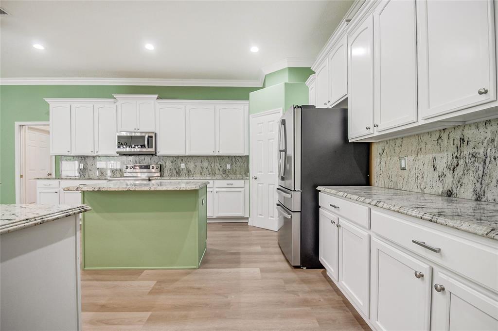 A kitchen with white cabinets and green walls opens into a living area with flooring — 8615 WARWICK SHORE CROSSING, ORLANDO, FL