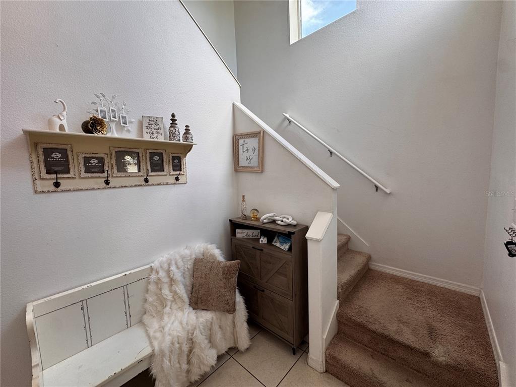A staircase with carpeted steps sits beside a white bench and a wooden storage cabinet — 2232 COLVILLE CHASE DRIVE, RUSKIN, FL