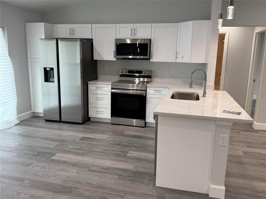A modern kitchen features white cabinets, stainless steel appliances, and a quartz-topped island — 15854 SW 38 PLACE, OCALA, FL