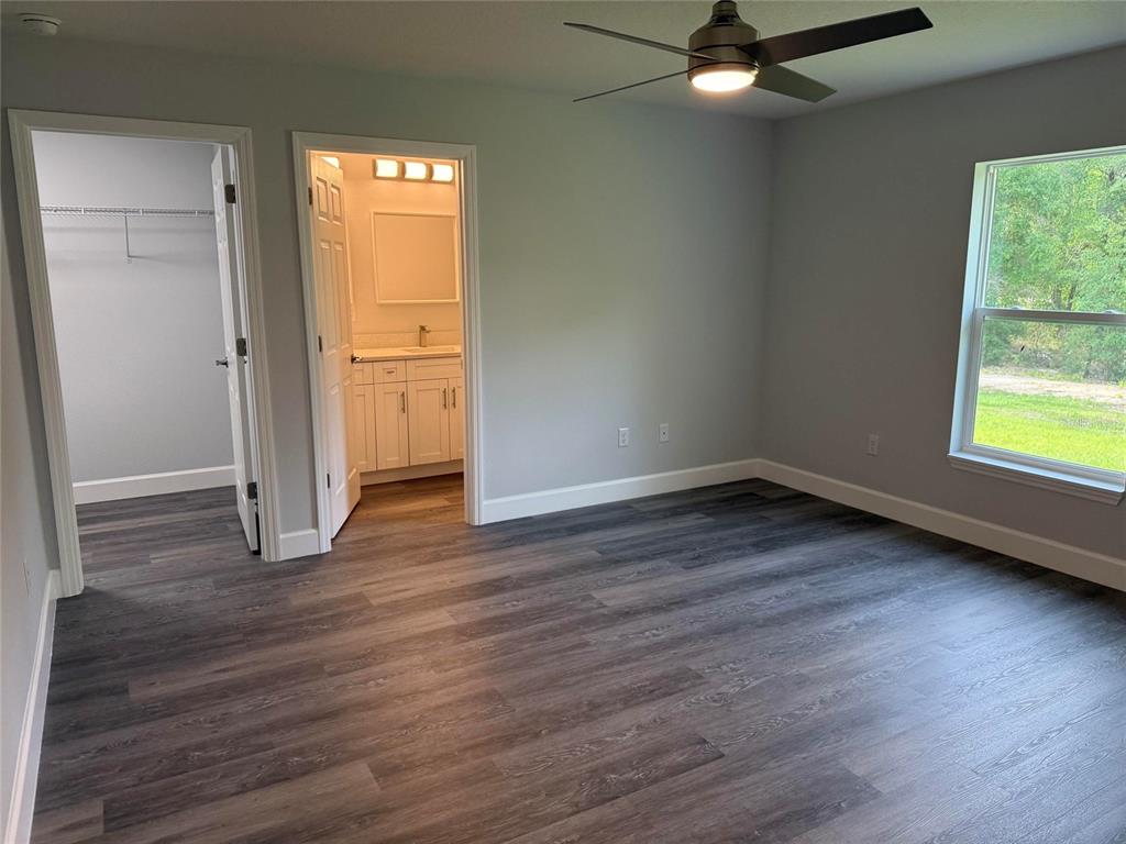 A bedroom with gray walls, wood-look flooring, a ceiling fan, and an attached bathroom — 15854 SW 38 PLACE, OCALA, FL