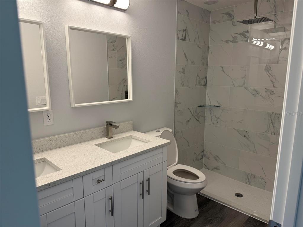 A bathroom features a double vanity with white cabinets, quartz countertops, and a tiled shower — 15854 SW 38 PLACE, OCALA, FL