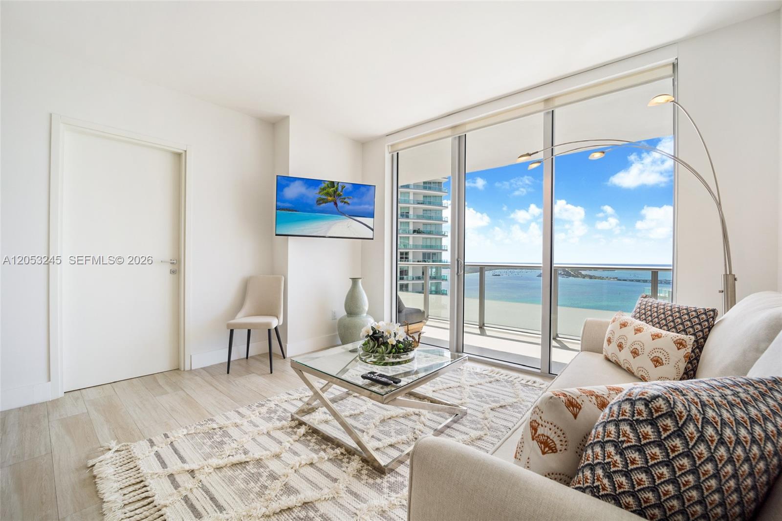 A bright living room features a glass coffee table, patterned pillows, and a balcony view — 1300 Brickell Bay Dr # 3004, Miami FL 33131, MIAMI, FL