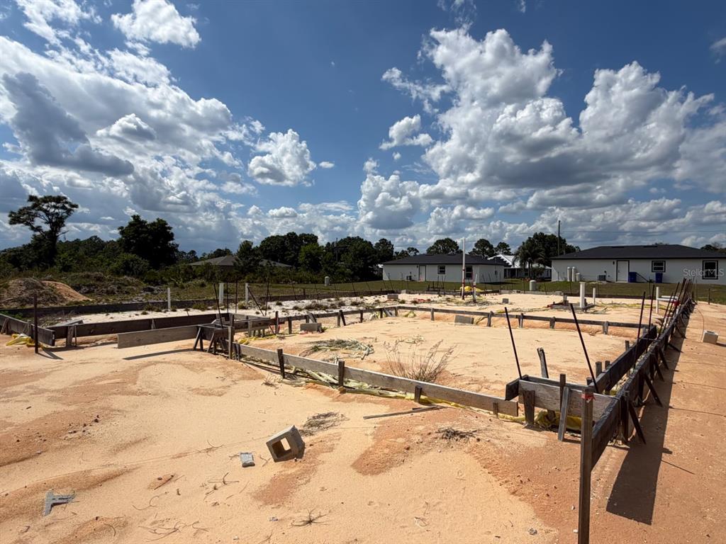 A residential construction site shows a sandy lot with wooden foundation forms and plumbing pipes — 7218 SUN N LAKE BOULEVARD, SEBRING, FL