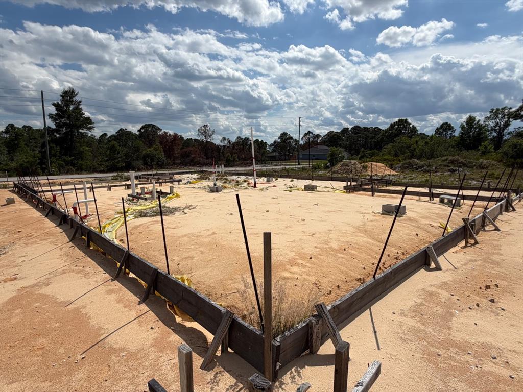 A construction site shows a wooden foundation form filled with sand and plumbing pipes — 7218 SUN N LAKE BOULEVARD, SEBRING, FL