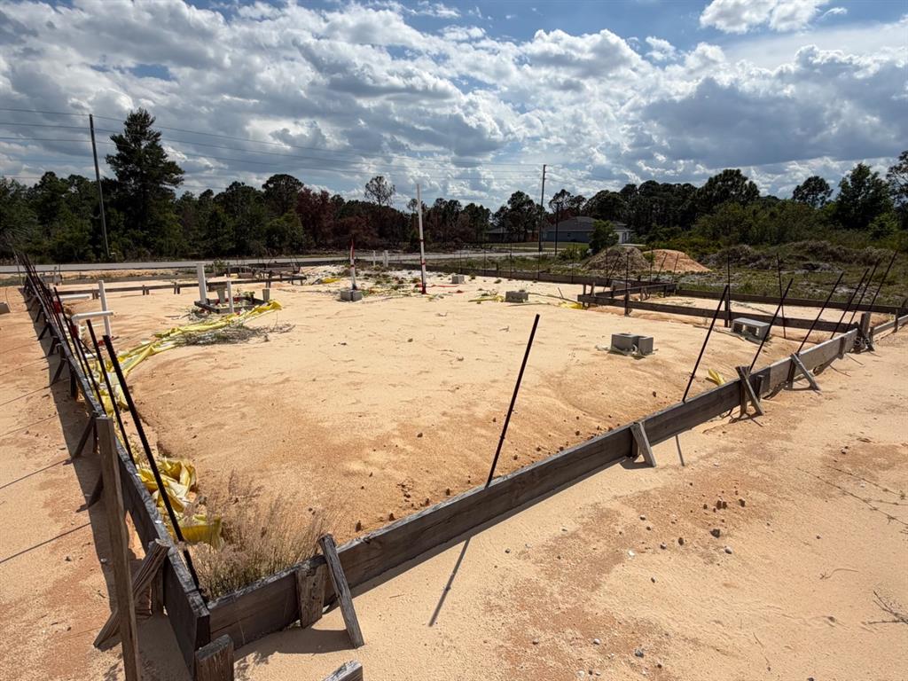 A residential construction site shows a sandy foundation lot framed with wooden boards and pipes — 7218 SUN N LAKE BOULEVARD, SEBRING, FL