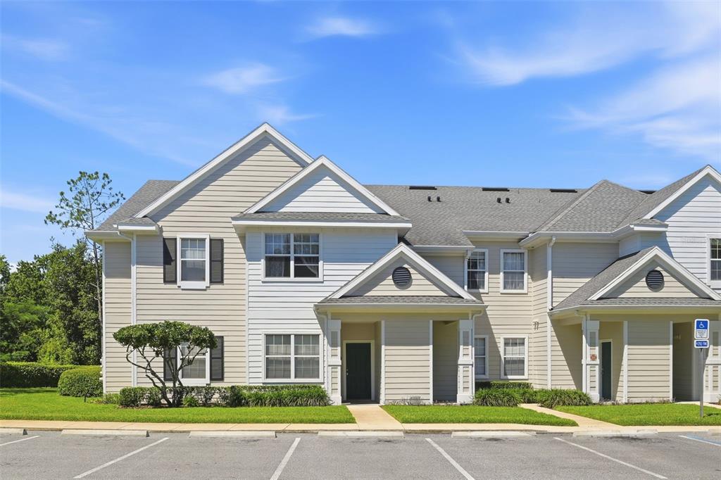 A two-story tan townhouse exterior with a parking lot in the foreground — 330 SOUTHERN PECAN CIRCLE UNIT 205, WINTER GARDEN, FL