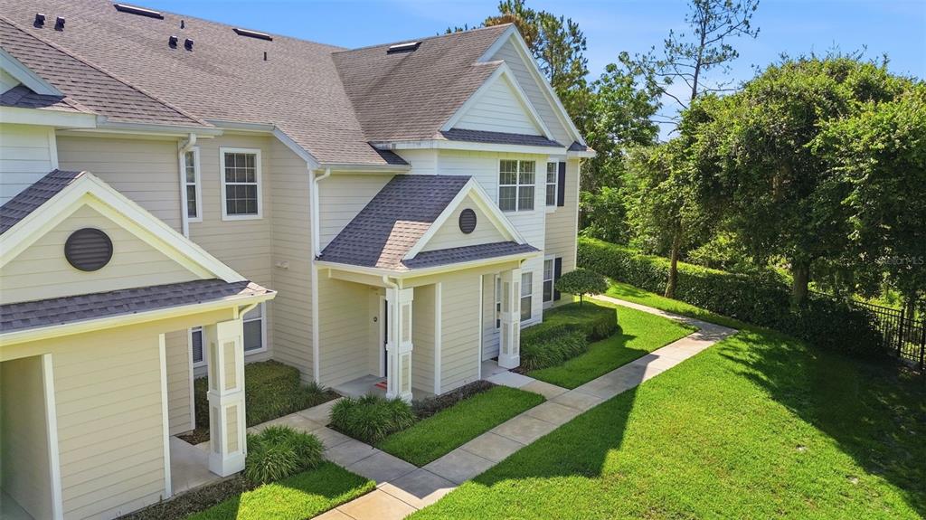An exterior view of a two-story beige townhouse with a shingled roof and sidewalk — 330 SOUTHERN PECAN CIRCLE UNIT 205, WINTER GARDEN, FL
