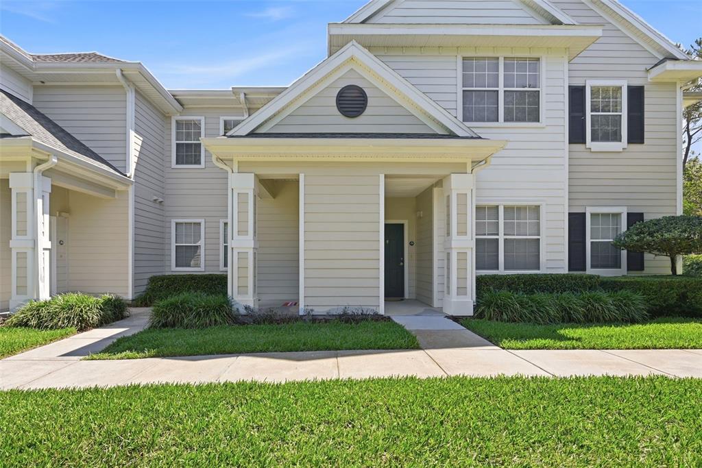 A two-story townhouse exterior with light siding, a covered entryway, and a front lawn — 330 SOUTHERN PECAN CIRCLE UNIT 205, WINTER GARDEN, FL