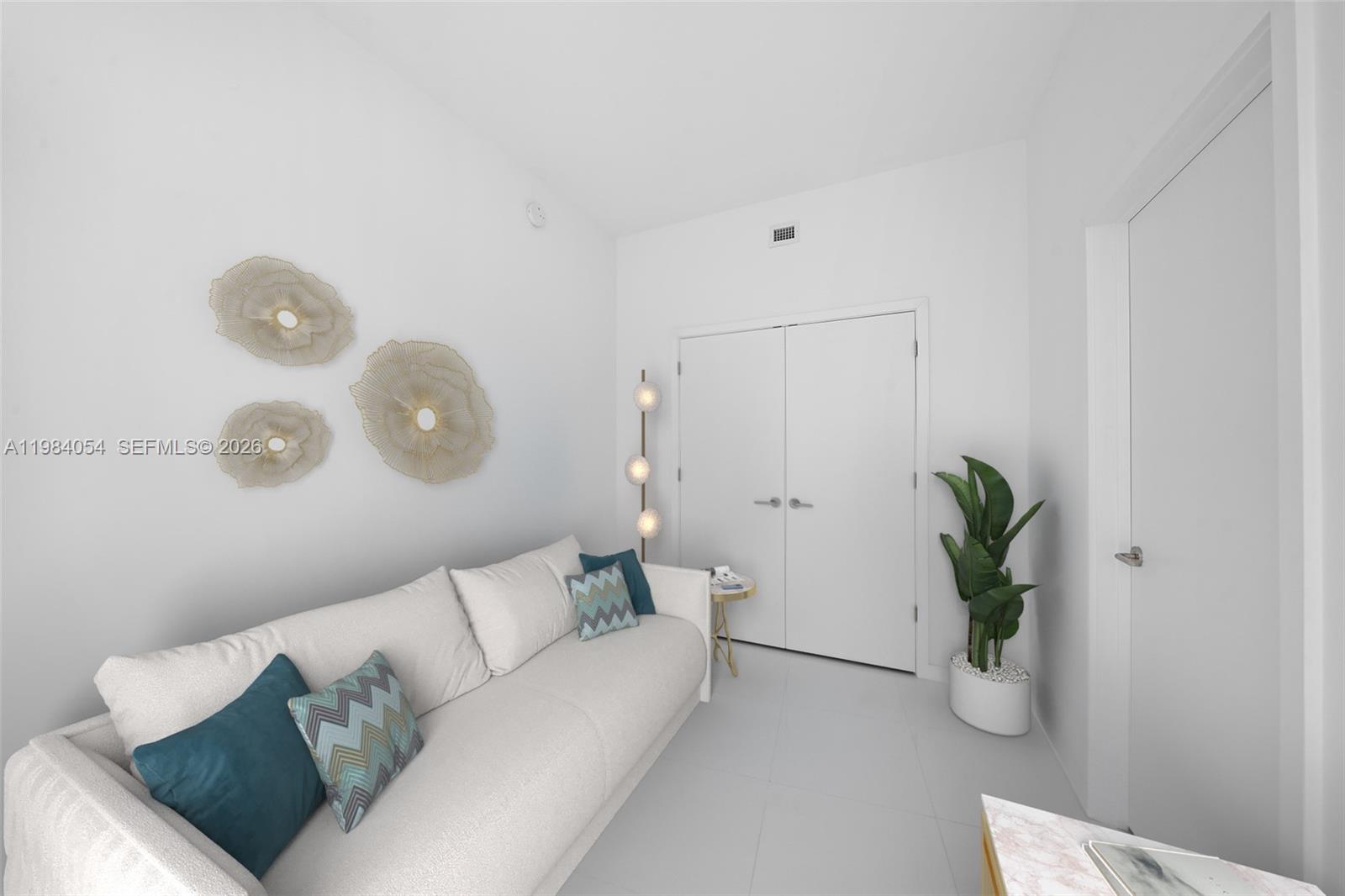 A white sofa with blue patterned pillows sits in a room with white walls — 851 NE 1st Ave # 4010, Miami FL 33132, MIAMI, FL