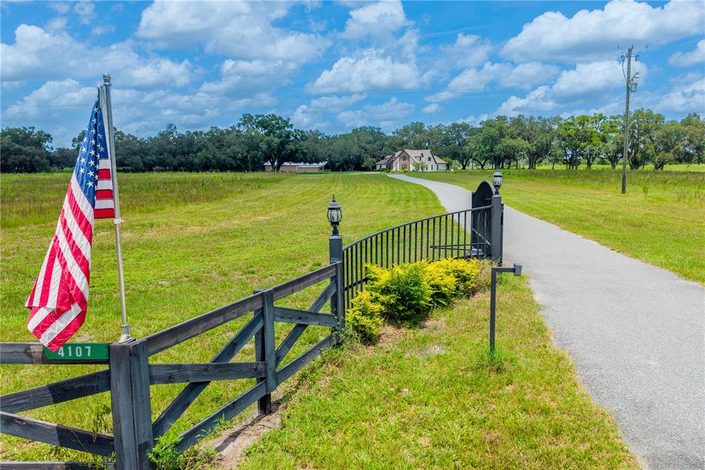 A long driveway leads to a house past a gated entrance with an American flag — 4107 SW STATE ROAD 45, NEWBERRY, FL