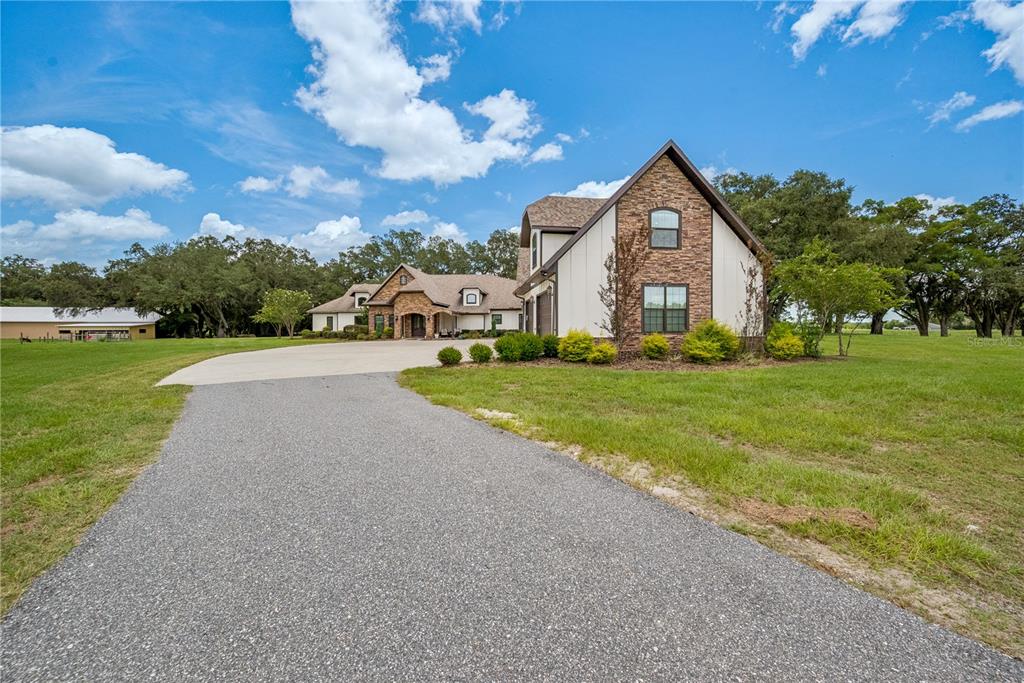 A large house with stone and white siding features a long driveway and grassy yard — 4107 SW STATE ROAD 45, NEWBERRY, FL
