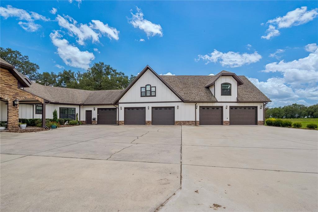 A large house exterior features a multi-car garage with white siding and stone accents — 4107 SW STATE ROAD 45, NEWBERRY, FL