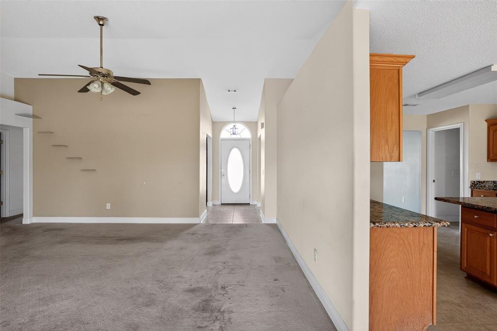 A living room with beige walls, carpeted flooring, and a ceiling fan leads to an entryway — 953 CHESAPEAKE TRAIL, CANTONMENT, FL