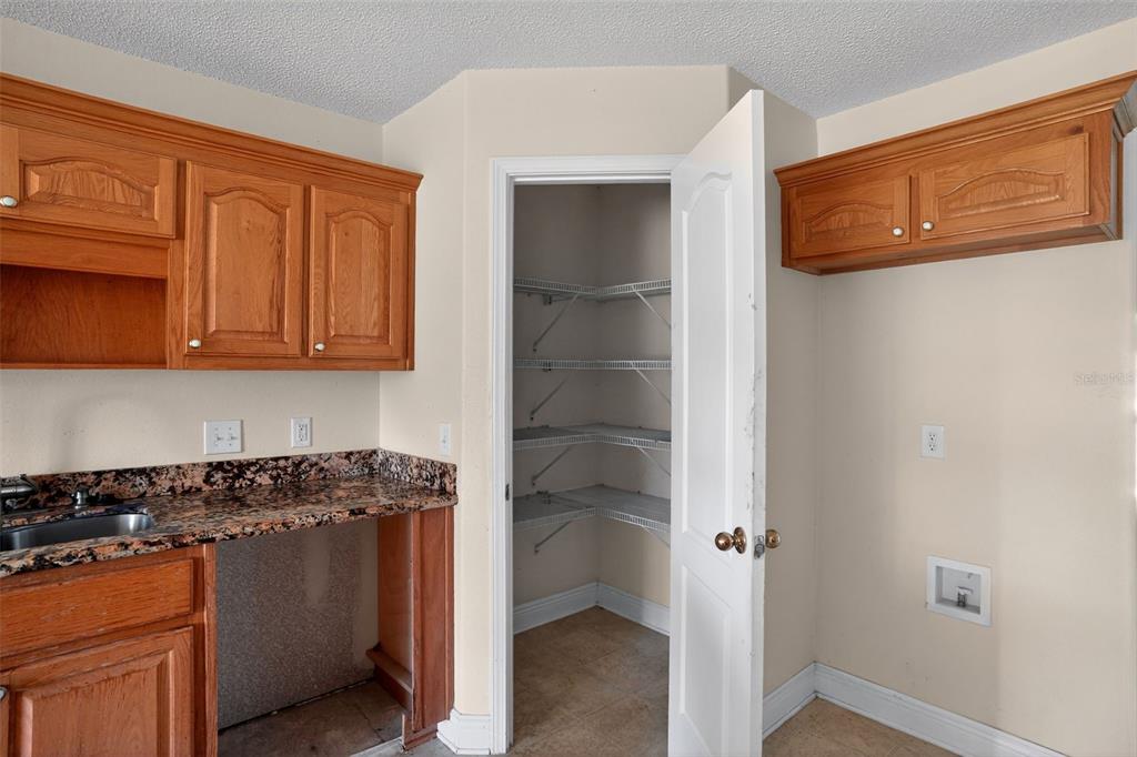 A kitchen area features wood cabinets, granite countertops, a sink, and an open pantry closet — 953 CHESAPEAKE TRAIL, CANTONMENT, FL