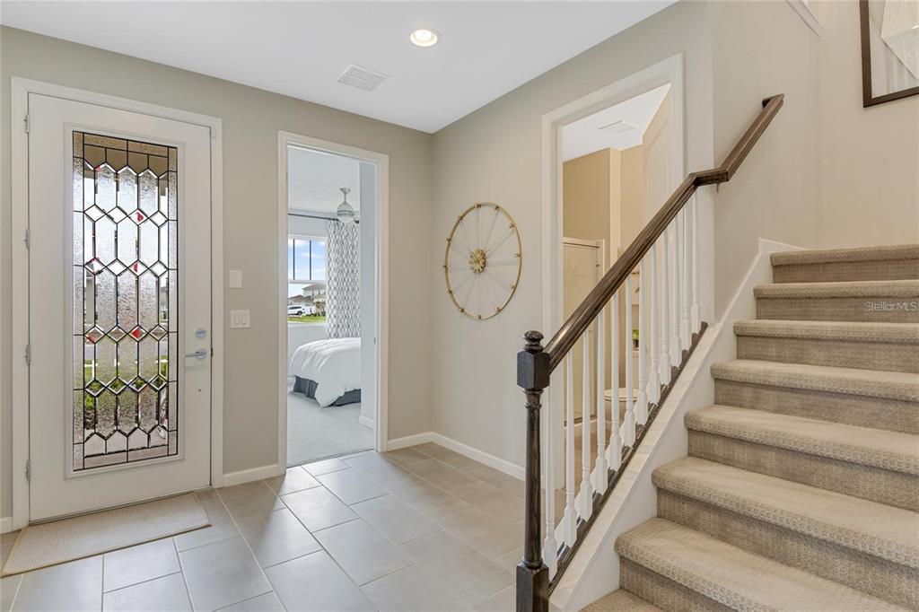 A foyer features tile flooring, a staircase with carpeted steps, and a glass-paneled front door — 168 FLAG LILLY LANE, UMATILLA, FL