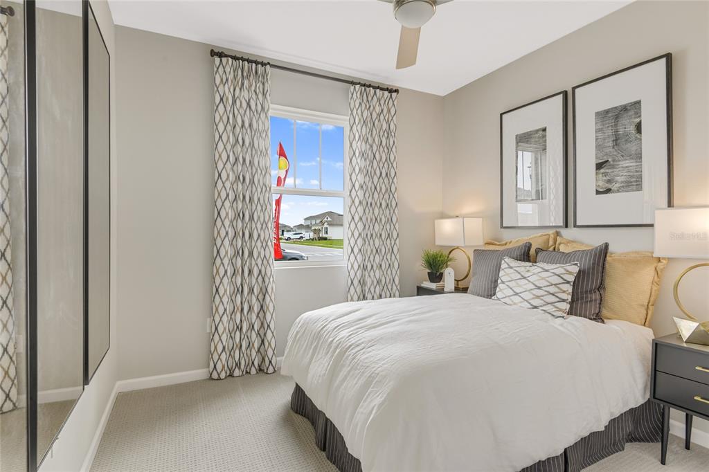 A bedroom features a bed with a white comforter, patterned curtains, and two framed prints — 168 FLAG LILLY LANE, UMATILLA, FL