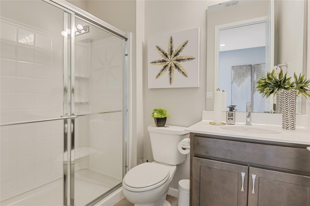 A bathroom features a glass-enclosed shower, a white toilet, and a dark wood vanity — 168 FLAG LILLY LANE, UMATILLA, FL