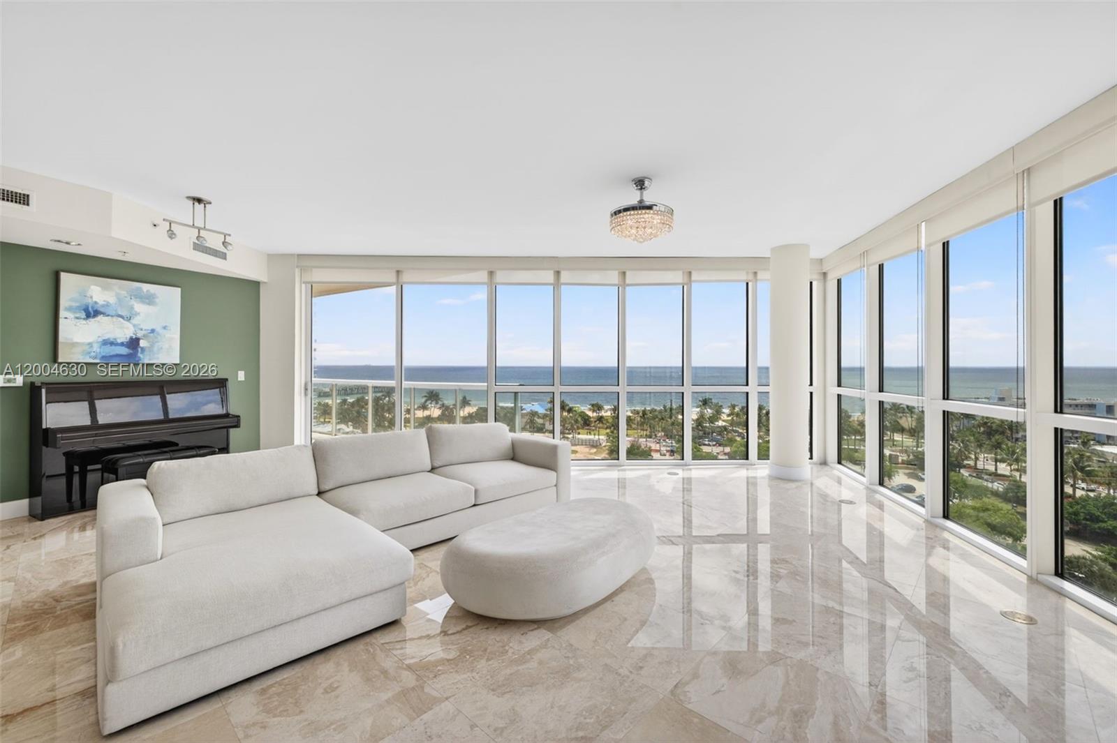 A living room with marble floors, a white sectional sofa, and floor-to-ceiling ocean views — 1 N Ocean Blvd # 806, Pompano Beach FL 33062, POMPANO BEACH, FL