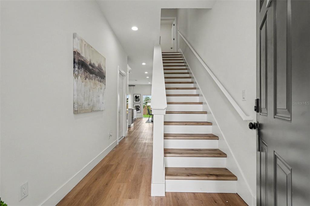An entryway features wood-look flooring, a staircase with white risers, and a dark front door — 3601 N 52ND STREET UNIT 1, TAMPA, FL