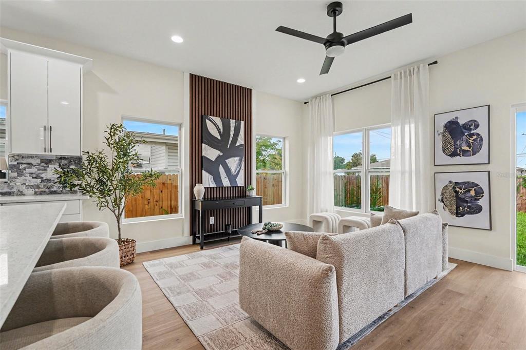 A modern living room features a slatted wood accent wall, neutral furniture, and light flooring — 3601 N 52ND STREET UNIT 1, TAMPA, FL