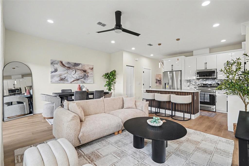 An open-concept living room and kitchen featuring a beige sofa, round coffee table, and island — 3601 N 52ND STREET UNIT 1, TAMPA, FL