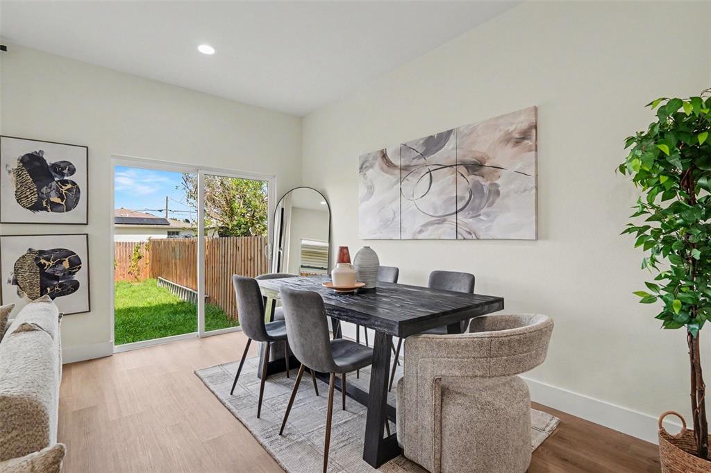 A dining room features a dark wooden table, gray chairs, and a sliding glass door — 3601 N 52ND STREET UNIT 1, TAMPA, FL