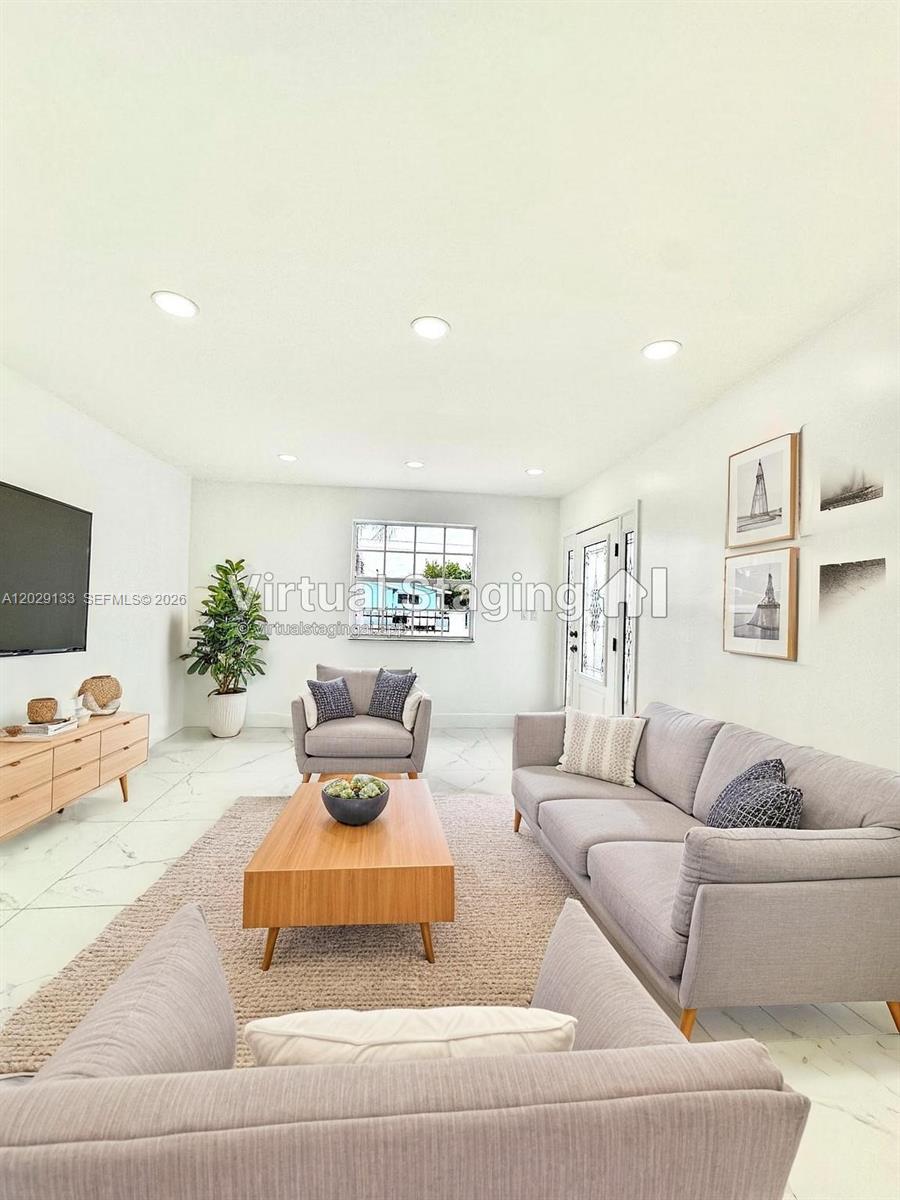 This living room features light-colored tile flooring, a gray sofa, and a wooden coffee table — HIALEAH, FL