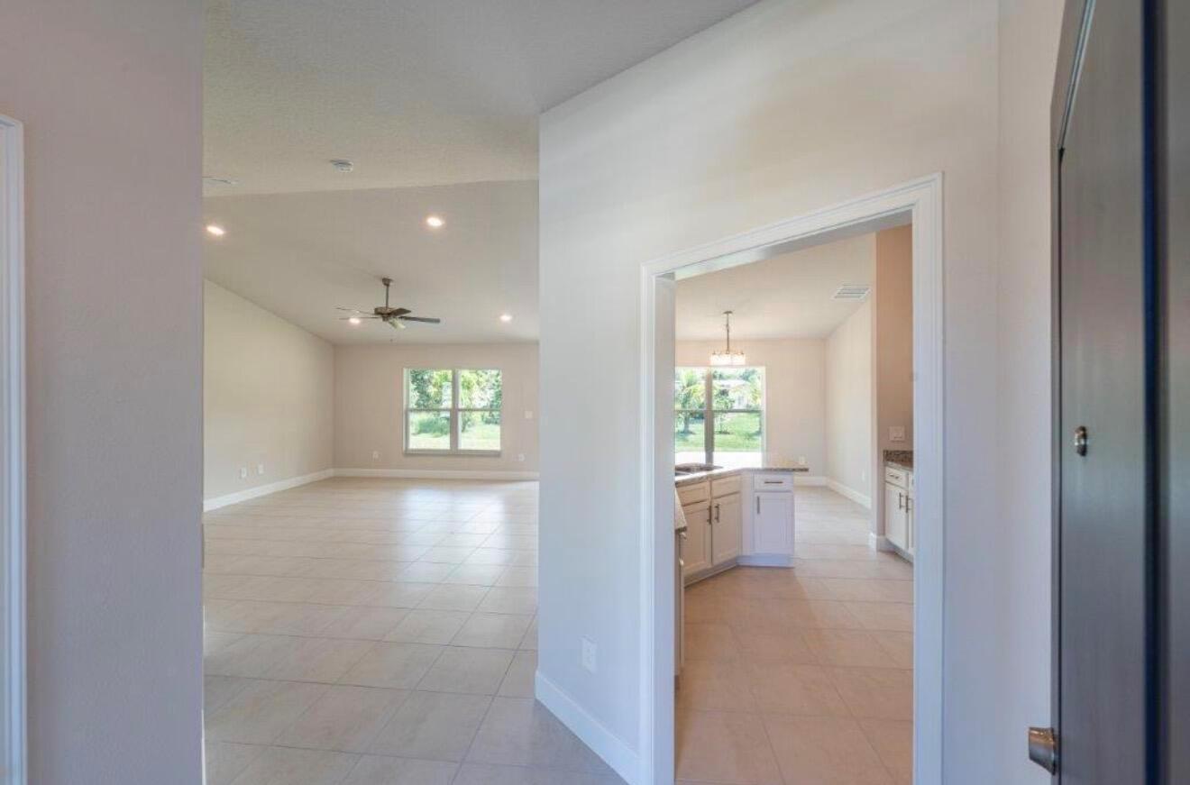 A view from a doorway looking into a living area and an adjacent kitchen — 7903 Penny Lane, Fort Pierce FL 34951, FORT PIERCE, FL