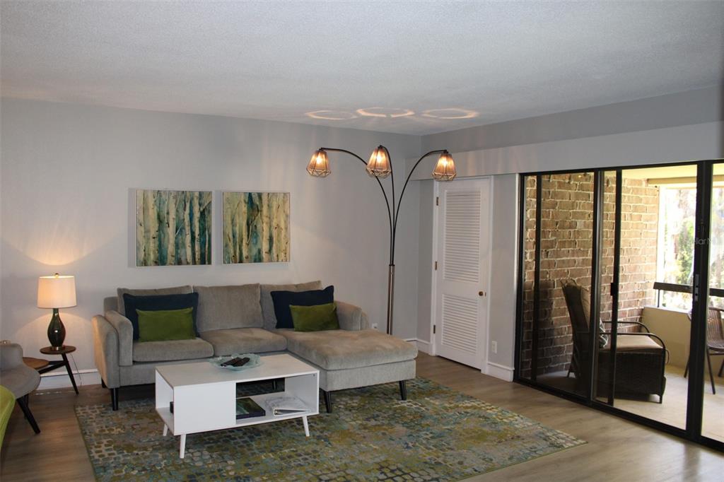 A living room features a gray sectional sofa, a white coffee table, and a floor lamp — 36750 US HIGHWAY 19 N UNIT 3-203, PALM HARBOR, FL