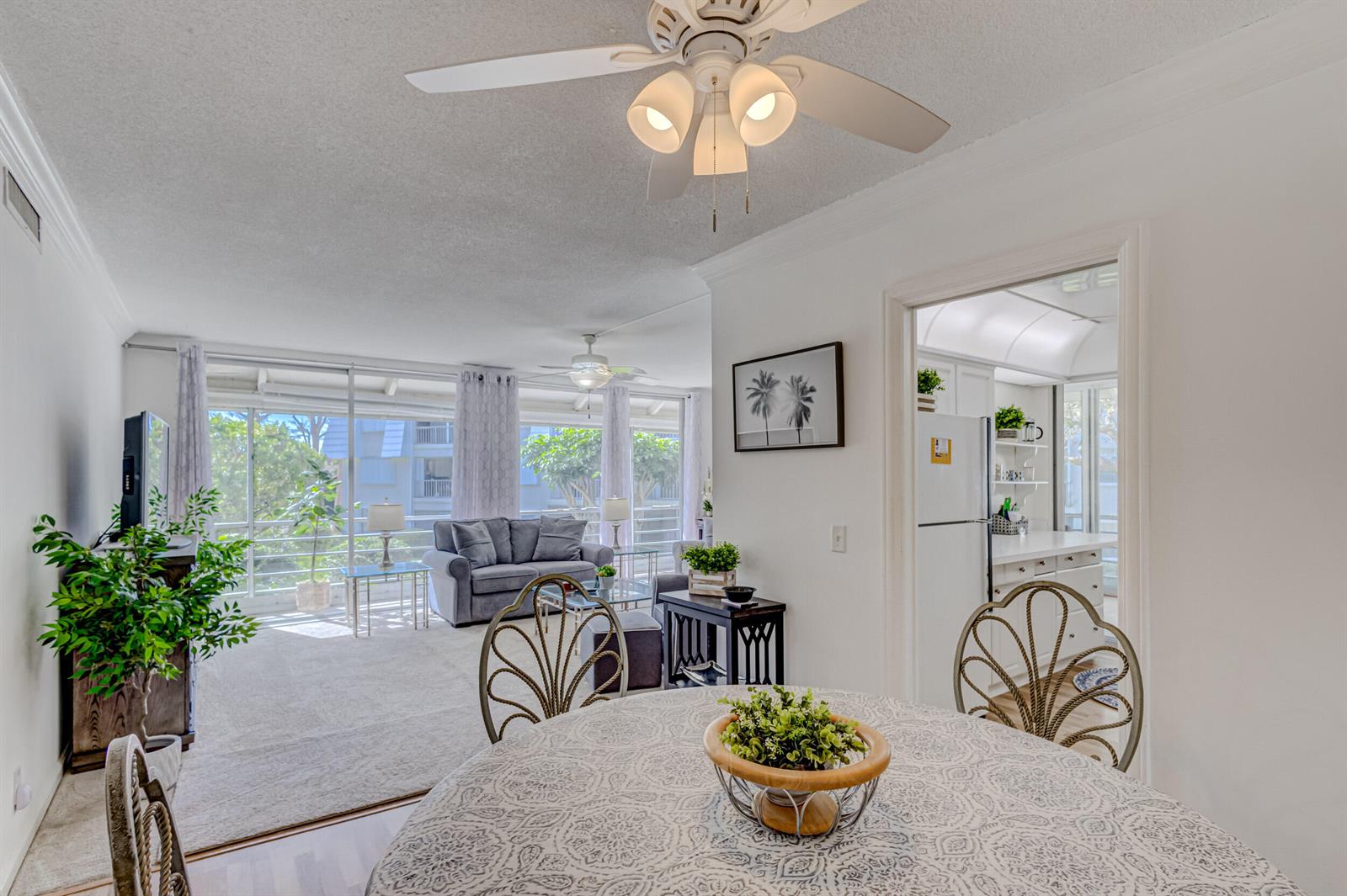 A dining area with a patterned tablecloth leads into a living room with large windows — 1201 Sugar Sands Boulevard, West Palm Beach FL 33404, WEST PALM BEACH, FL