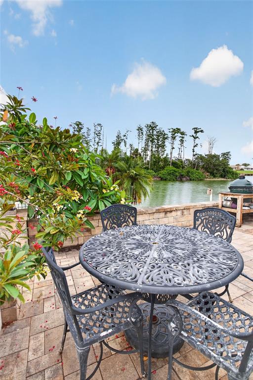 A patio with a metal table and chairs overlooks a lake and trees — 1411 JACOBSON CIRCLE, SUN CITY CENTER, FL