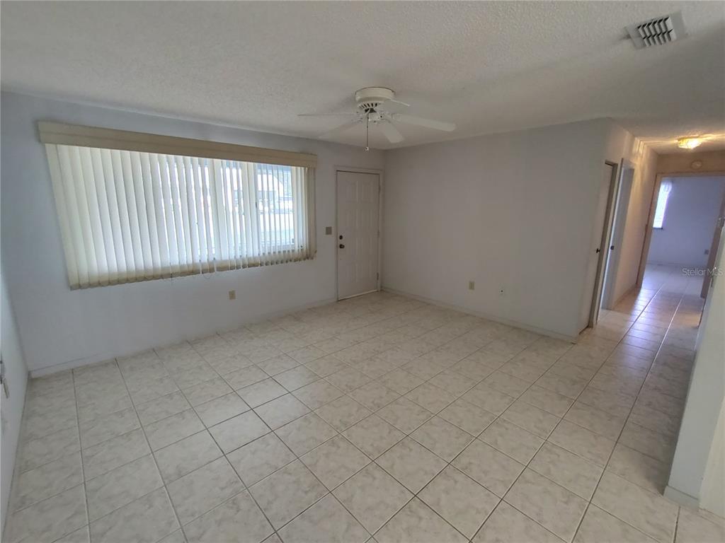 A room with light-colored tile flooring, a ceiling fan, and a large window with blinds — 8690 SW 108TH PLACE, OCALA, FL