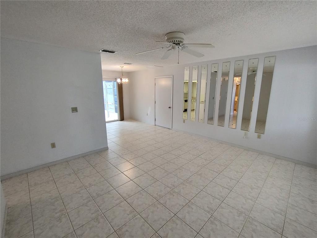 A room with white tiled floors, a ceiling fan, and a wall of vertical mirrors — 8690 SW 108TH PLACE, OCALA, FL