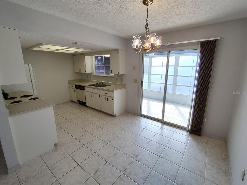 A kitchen and dining area with white cabinets, tile flooring, and a sliding glass door — 8690 SW 108TH PLACE, OCALA, FL