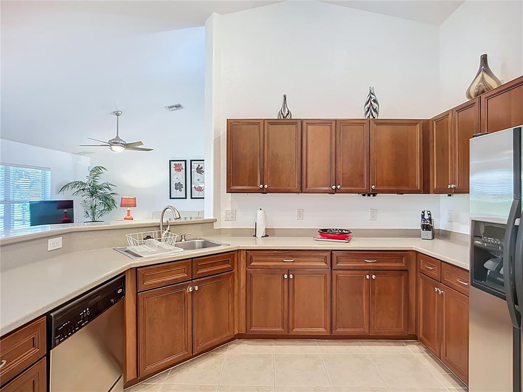 A kitchen features wood cabinets, light countertops, stainless steel appliances, and tile flooring — 123 MARKER ROAD, ROTONDA WEST, FL