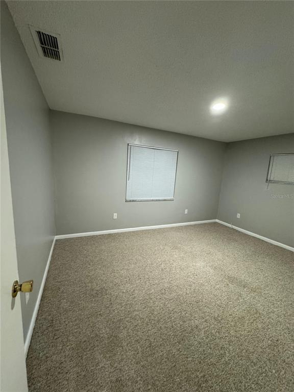 An empty bedroom features gray walls, beige carpeting, and two windows with white blinds — 2526 ELM AVE, LAKE WALES, FL