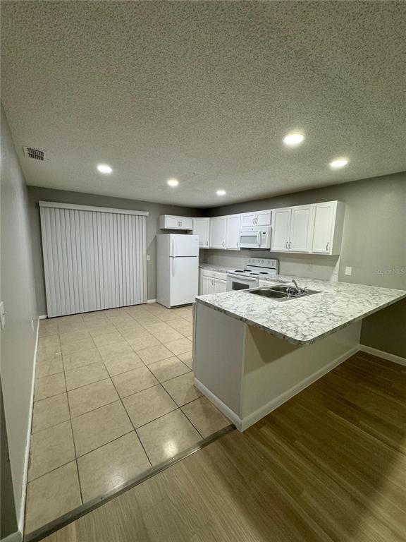 A kitchen features white cabinets, a marble-patterned countertop, a breakfast bar, and tiled flooring — 2526 ELM AVE, LAKE WALES, FL