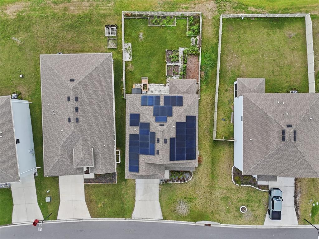 An aerial view shows a suburban house with solar panels on the roof and a backyard — 1516 TROPICAL OASIS AVENUE, PLANT CITY, FL