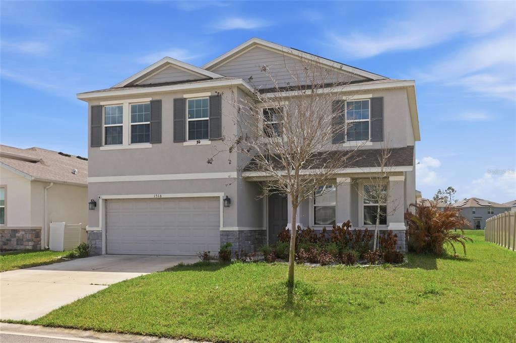 A two-story house with a gray exterior, stone accents, and a two-car garage — 1516 TROPICAL OASIS AVENUE, PLANT CITY, FL