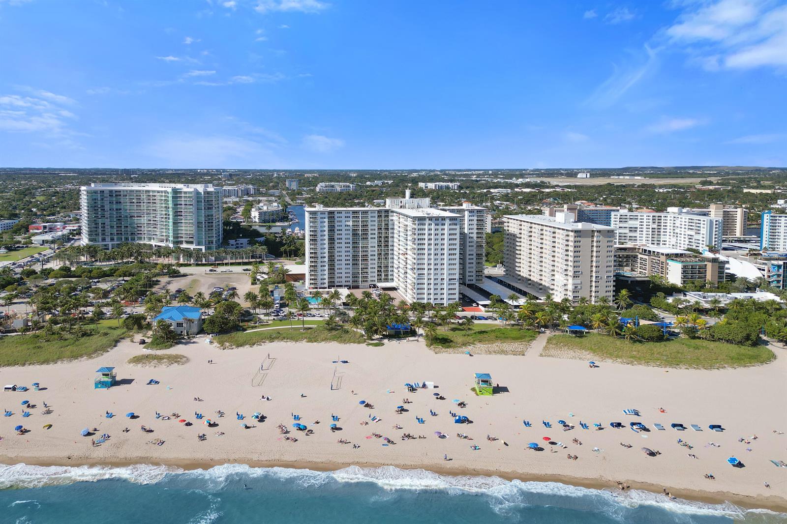 An aerial view of a sandy beach with people and high-rise buildings in the background — 111 N Pompano Beach Boulevard # 411, Pompano Beach FL 33062, POMPANO BEACH, FL