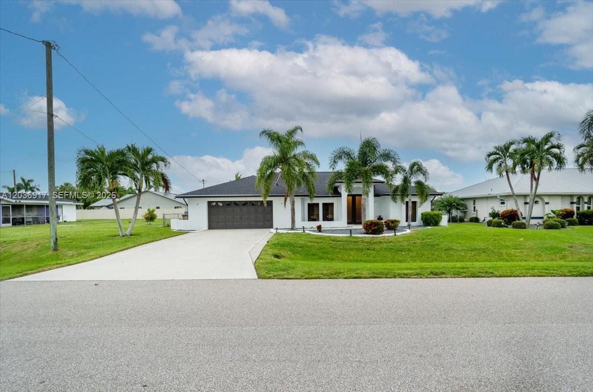 A white single-story house with a dark roof and palm trees sits on a lawn — 3728 SE 18 Ave, Cape Coral FL 33904, CAPE CORAL, FL