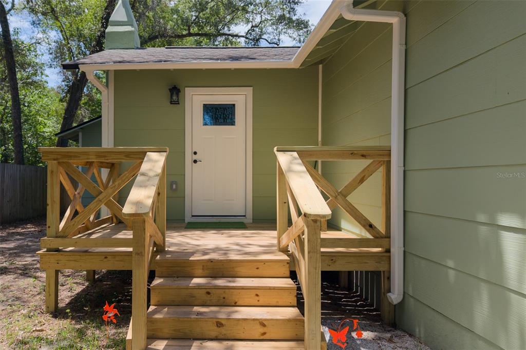 A wooden deck with stairs and railings leads to a white door on a house — 1935 NW 33RD AVENUE, GAINESVILLE, FL