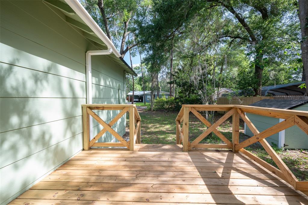 A wooden deck with X-pattern railings overlooks a backyard with trees and a shed — 1935 NW 33RD AVENUE, GAINESVILLE, FL
