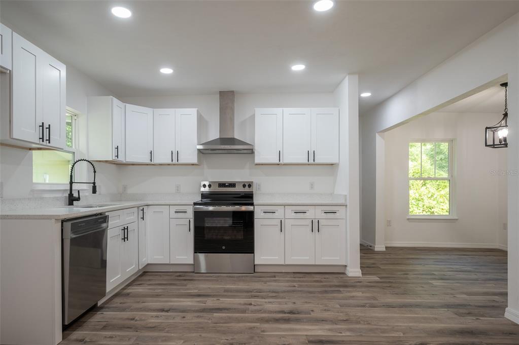 A kitchen with white cabinets, stainless steel appliances, and wood-look flooring — 1935 NW 33RD AVENUE, GAINESVILLE, FL