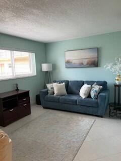 A living room features a blue sofa, a dark wood media console, and light-colored walls — 705 Lori Drive # 210, Palm Springs FL 33461, PALM SPRINGS, FL