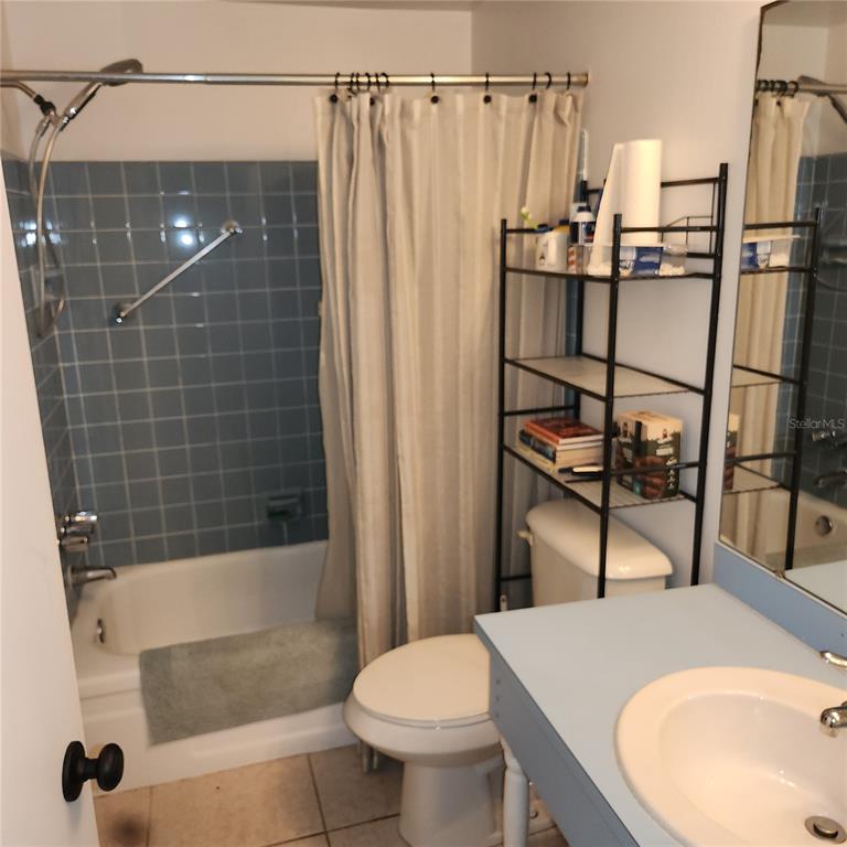 A bathroom features a blue-tiled shower, a toilet with a metal shelving unit, and a vanity — 4070 GROBE STREET, NORTH PORT, FL