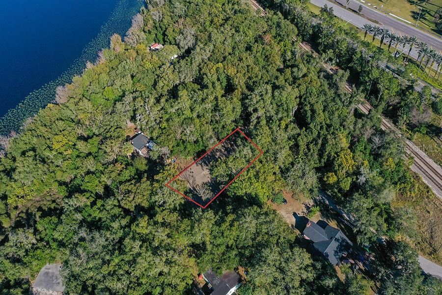 An aerial view shows a rectangular plot of land outlined in red amidst dense trees — 1130 MECHANIC STREET, MAITLAND, FL