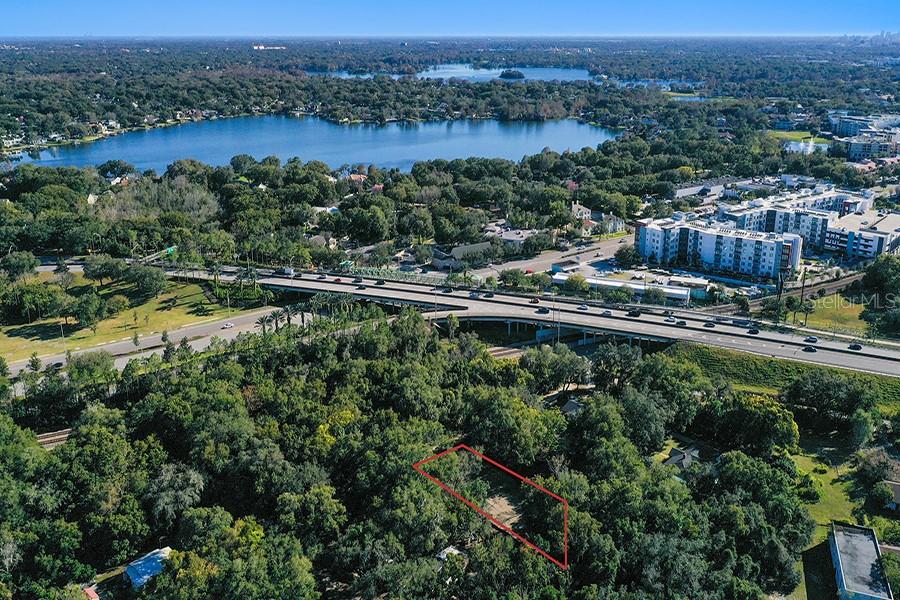 An aerial view shows a rectangular plot of land outlined in red amidst dense trees — 1130 MECHANIC STREET, MAITLAND, FL