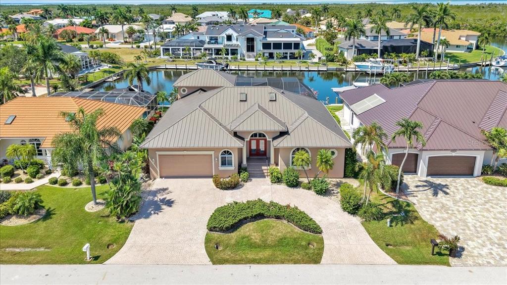 An aerial view shows a tan house with a metal roof and a circular driveway — 3651 ARUBA COURT, PUNTA GORDA, FL